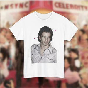 Peut inclure: T-shirt blanc avec une image en noir et blanc d'un homme aux cheveux foncés portant une chemise gris clair. L'image est centrée sur le t-shirt et il y a de petits cœurs roses dans les coins supérieurs de l'image.