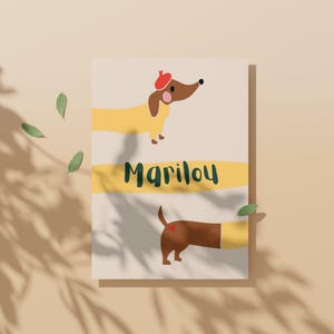 May include: A whimsical illustration features a dachshund wearing a red beret. The dog is yellow and brown, with the name "Marilou" in green script across a yellow stripe. The bottom half shows the dog's rear with a heart.