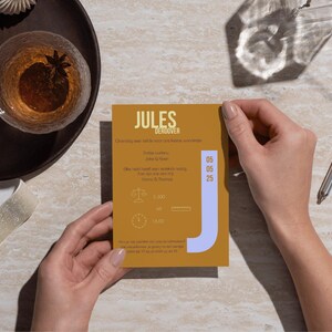 May include: A yellow card with the text "Jules Deroover" in black. The card has a blue "J" on the right side and the date "06 06 25" on the right side. The card also has a scale and a clock with the text "1.000" and "1.662" on the card.