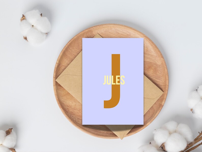 May include: A light blue card with a large brown letter "J" and the word "JULES" in yellow letters.