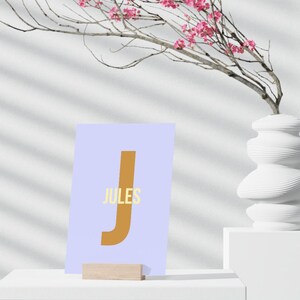 May include: A light blue card with a large brown letter "J" and the word "JULES" in yellow text.