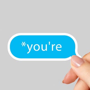 May include: A blue speech bubble sticker with the text "*you're" in white. The sticker is held by a hand with a light gray background.