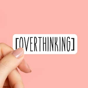 May include: A white rectangular sticker with the word "OVERTHINKING" in black, held by a hand with a pink background. The sticker has rounded corners and a black border. The text is in a tall, thin font.