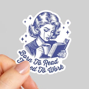 May include: A blue and white sticker featuring a vintage illustration of a woman reading a book and holding a mug, with a tear rolling down her cheek. The sticker has the text "Born To Read, Forced To Work".