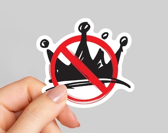May include: A sticker with a black crown design crossed out by a red prohibition sign. The crown has a hand-drawn style and a white border. The sticker is held by a hand.