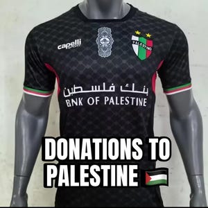 May include: Black soccer jersey with a green, white, and red logo that says "Palestino" and two gold stars. The jersey also has the text "Bank of Palestine" in Arabic and English. The jersey is on a mannequin and has the text "Donations to Palestine" and a Palestinian flag.