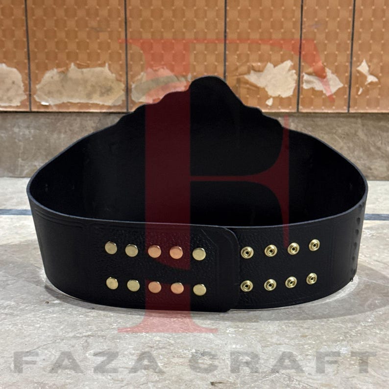 May include: Black leather championship belt with gold-colored studs. The belt has a curved shape and a large, decorative top. The text "FAZA CRAFT" is visible at the bottom of the image.