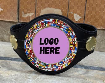 May include: Black leather championship belt with a central medallion. The medallion is surrounded by a ring of international flags and features the text "LOGO HERE". Gold-colored accents are on the sides of the belt.