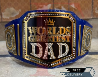 May include: A blue and gold championship belt with the words "Worlds Greatest Dad" in gold lettering. The belt has a black centre plate with a gold crown and is decorated with rhinestones.