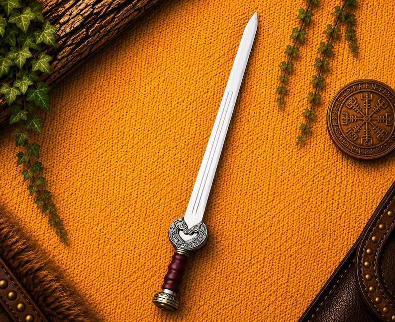 May include: A double-edged steel sword featuring a pointed blade with a central fuller. The hilt includes a dark maroon grip, a metallic pommel, and an ornate, silver-toned crossguard decorated with intricate, swirling embossed patterns.