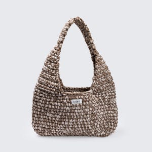 May include: A brown and white crocheted tote bag with a single strap. The bag has a small white label with the text "LOOPS" on it.