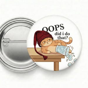 May include: A round button with a cartoon cat wearing a maroon hat, lying on a table with a spilled glass of ice cubes. The text reads "OOPS did I do that?"