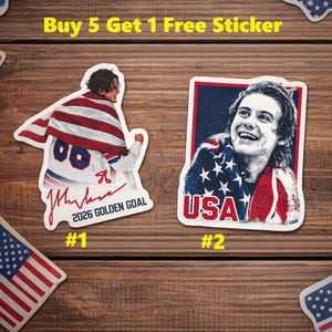 May include: Two stickers featuring a person in a USA flag-themed design. One sticker has the text "2026 GOLDEN GOAL" and the number "#1". The other sticker has the word "USA" and the number "#2".