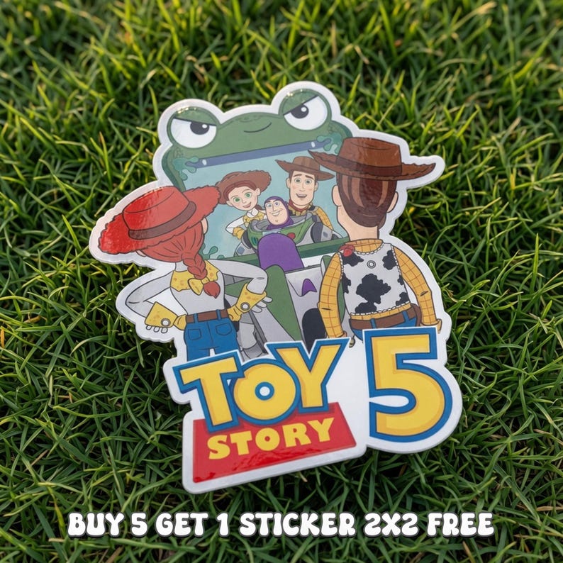 Pode incluir: Um adesivo recortado com personagens de Toy Story, incluindo Woody, Jessie e Buzz Lightyear, dentro de um ve&iacute;culo em forma de sapo verde. O texto diz Toy Story 5. O adesivo mede 5x5 cm e tem uma borda branca com acabamento brilhante.
