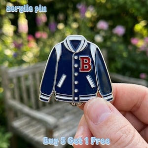 Pode incluir: Um pin de acrílico azul marinho e branco em forma de casaco universitário com um "B" vermelho no peito. O pin tem detalhes brancos e uma borda prateada. O texto "acrylic pin" está no topo e "Buy 5 Get 1 Free" na parte inferior.