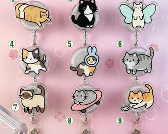May include: Nine retractable badge reels featuring various cartoon cat designs, including a cat shaped like a loaf of bread, a cat with fairy wings, and a cat on a skateboard. Each reel is numbered one through nine with the text Buy 8 Get 1 Free.