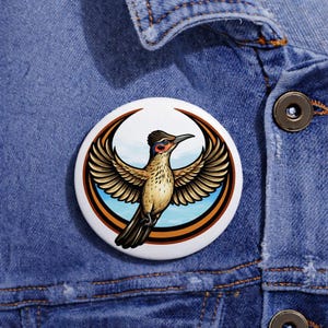 May include: A circular badge with a detailed illustration of a bird with outstretched wings. The bird has brown, tan, and black feathers, a red and black head, set against a blue sky within a brown and white circular frame.