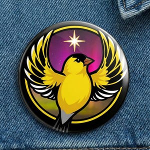 Puede incluir: Un botón redondo con un diseño de pájaro amarillo. El pájaro tiene las alas extendidas y está sobre un fondo morado y verde con una estrella. El botón tiene un borde negro y está sobre un fondo de mezclilla azul.