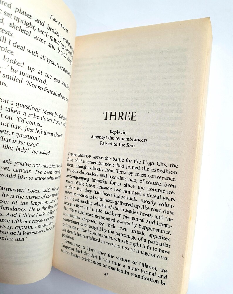 Puede incluir: Libro abierto con texto en p&aacute;ginas amarillentas. El t&iacute;tulo del cap&iacute;tulo "THREE" es visible, junto con los subt&iacute;tulos "Replevin", "Amongst the remembrancers" y "Raised to the four". El texto es de una novela.