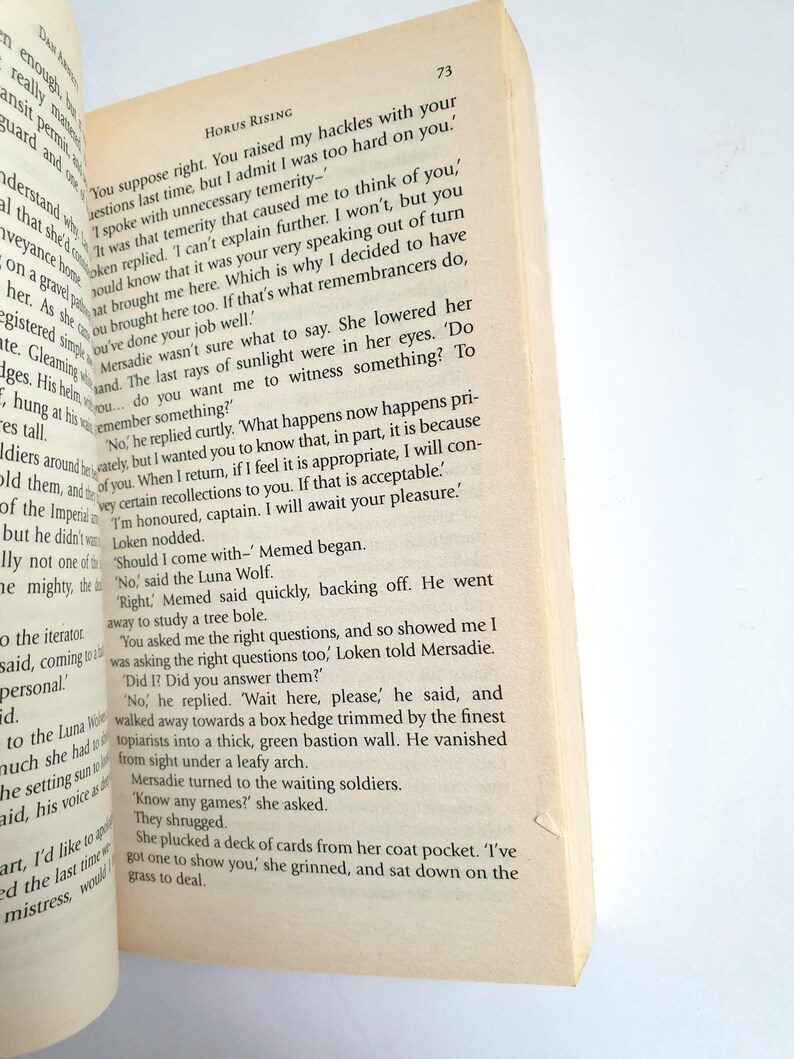 Puede incluir: Libro abierto con texto sobre papel envejecido. El t&iacute;tulo "HORUS RISING" es visible en la parte superior de la p&aacute;gina. El texto est&aacute; en fuente negra. El n&uacute;mero de p&aacute;gina "73" est&aacute; en la esquina superior derecha.