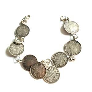 May include: A silver bracelet made from vintage Canadian coins. The coins are linked with silver connectors. Each coin has text and a portrait. The bracelet is shown on a white background.