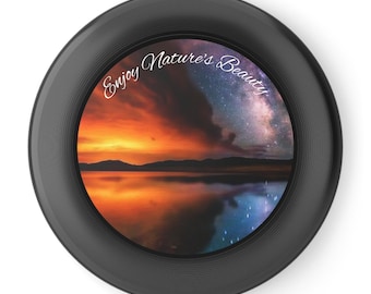 Può includere: Un oggetto rotondo e nero con un paesaggio con un tramonto su un lago, che riflette i colori del cielo. Il testo "Enjoy Nature's Beauty" è scritto in script in alto. L'immagine è incorniciata da un bordo nero.
