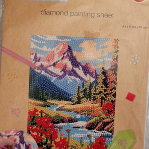 May include: Diamond painting kit featuring a colorful landscape with mountains, a river, and trees. The kit includes a 6x8 inch canvas, beads, and tools. Crafter's Square diamond painting sheet.