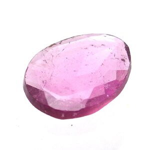 May include: A faceted, teardrop-shaped gemstone in shades of pink and magenta. The gem has a polished surface with visible internal inclusions. The stone is set against a white background, highlighting its color and clarity. Ideal for jewelry making.