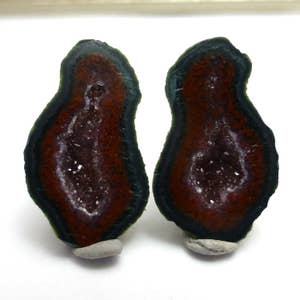May include: Two agate slices with a dark green outer layer and a red inner layer. The inner layer has a crystal-like texture.