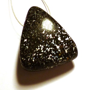 May include: A black triangular pendant with white and iridescent flecks. The pendant is hanging from a thin white cord.