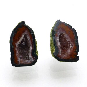 May include: Two halves of a geode with a brown, green, and black exterior. The interior of the geode is filled with clear quartz crystals.