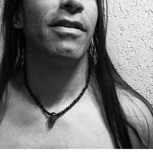 May include: A black beaded necklace with a skull pendant. The necklace is worn by a person with long black hair.