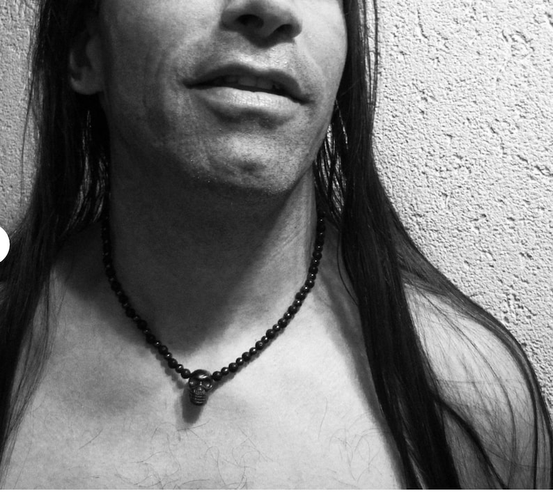 May include: A black beaded necklace with a skull pendant. The necklace is worn by a person with long black hair.