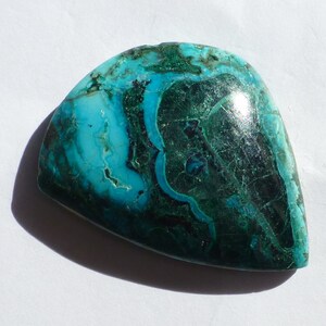May include: A smooth, polished, green and blue gemstone with a unique, swirling pattern. The gemstone is a natural, organic material with a variety of colors and textures.