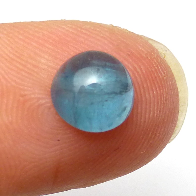 K&ouml;nnte beinhalten: Ein runder, hellblauer Edelstein mit einer glatten, polierten Oberfl&auml;che.