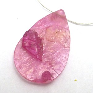 May include: A pink teardrop-shaped pendant with a smaller pink crystal embedded in the center.