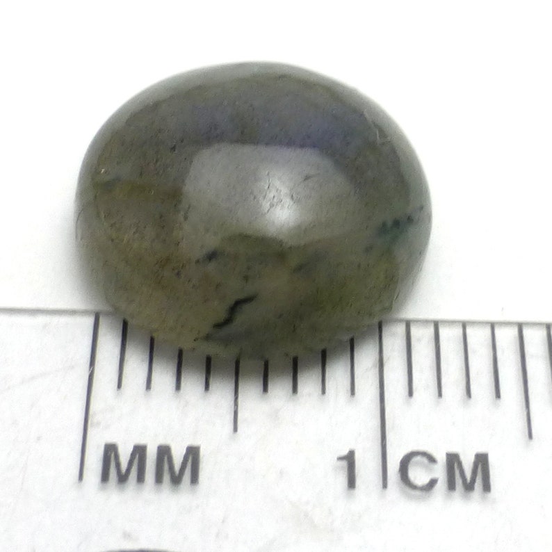 May include: A green oval-shaped gemstone with a smooth, polished surface. The stone is approximately 1 centimeter in length.