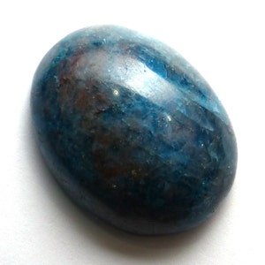 May include: Oval-shaped polished gemstone with a mix of blue, teal, and brown hues. The stone has a smooth, glossy surface and a natural, organic appearance. The gemstone is set against a white background.