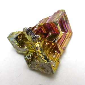 以下が含まれることがあります： メタリックな光沢を持つ、カラフルなビスマス結晶。 金、紫、赤など、鮮やかな色の配列を示しています。 結晶の幾何学的な構造がはっきりと見え、そのユニークな形が際立っています。 これは天然の鉱物標本です。