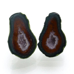 May include: Two halves of a geode with a green, brown, and purple interior. The geode is cut in half and polished to reveal the crystals inside.