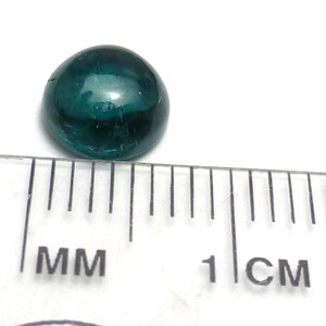 K&ouml;nnte beinhalten: Ein dunkelgr&uuml;ner Cabochon-Edelstein mit einem Durchmesser von etwa 1 cm.