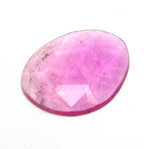 May include: A pink oval-shaped gemstone with a faceted cut. The gemstone is translucent and has a slight shimmer.