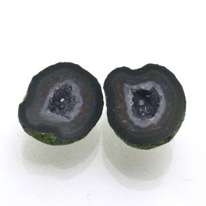 May include: Two halves of a geode with a black exterior and a white interior with a crystal cluster. The geode is about 2 inches in diameter.