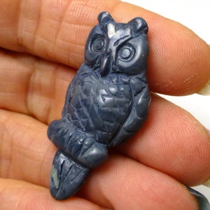 Könnte beinhalten: Eine geschnitzte blaue Eulenfigur aus Stein. Die Eule hat detaillierte Merkmale, darunter Augen, Schnabel und Federn.