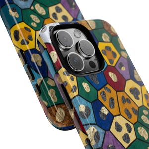 May include: A colorful phone case with a geometric pattern. The case features a mosaic design with various colors, including blue, green, yellow, and red. Gold leaf accents are scattered throughout the design. The phone case has a black camera lens.