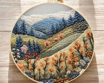 May include: Embroidered hoop art depicting a landscape with blue mountains, green hills, and orange flowers. The hoop is made of wood and has a light brown finish.