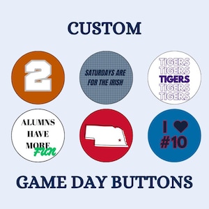 Pode incluir: Uma coleção de botões personalizados para o dia do jogo. Os botões apresentam vários designs, incluindo o número 2, o texto "Saturdays are for the Irish", a palavra "Tigers" repetida, o texto "Alums have more fun", um contorno de Nebraska e "I heart #10".