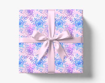 May include: A present wrapped in paper with a pale pink background and a pattern of blue, purple, and white snowflakes. It is tied with a light pink ribbon and bow.