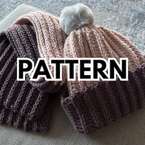 May include: Two crocheted hats, one in a light pink color and one in a dark brown color. The pink hat has a fluffy white pompom on top. The hats are laid out on a light gray surface. The word "PATTERN" is written in large black letters across the image.