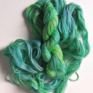 Peut inclure: Une &eacute;cheveau de fil teint &agrave; la main dans des tons de vert et de sarcelle. Le fil est d'un poids fin et doux, parfait pour les projets de tricot ou de crochet. Les couleurs se m&eacute;langent, cr&eacute;ant un effet de d&eacute;grad&eacute;.